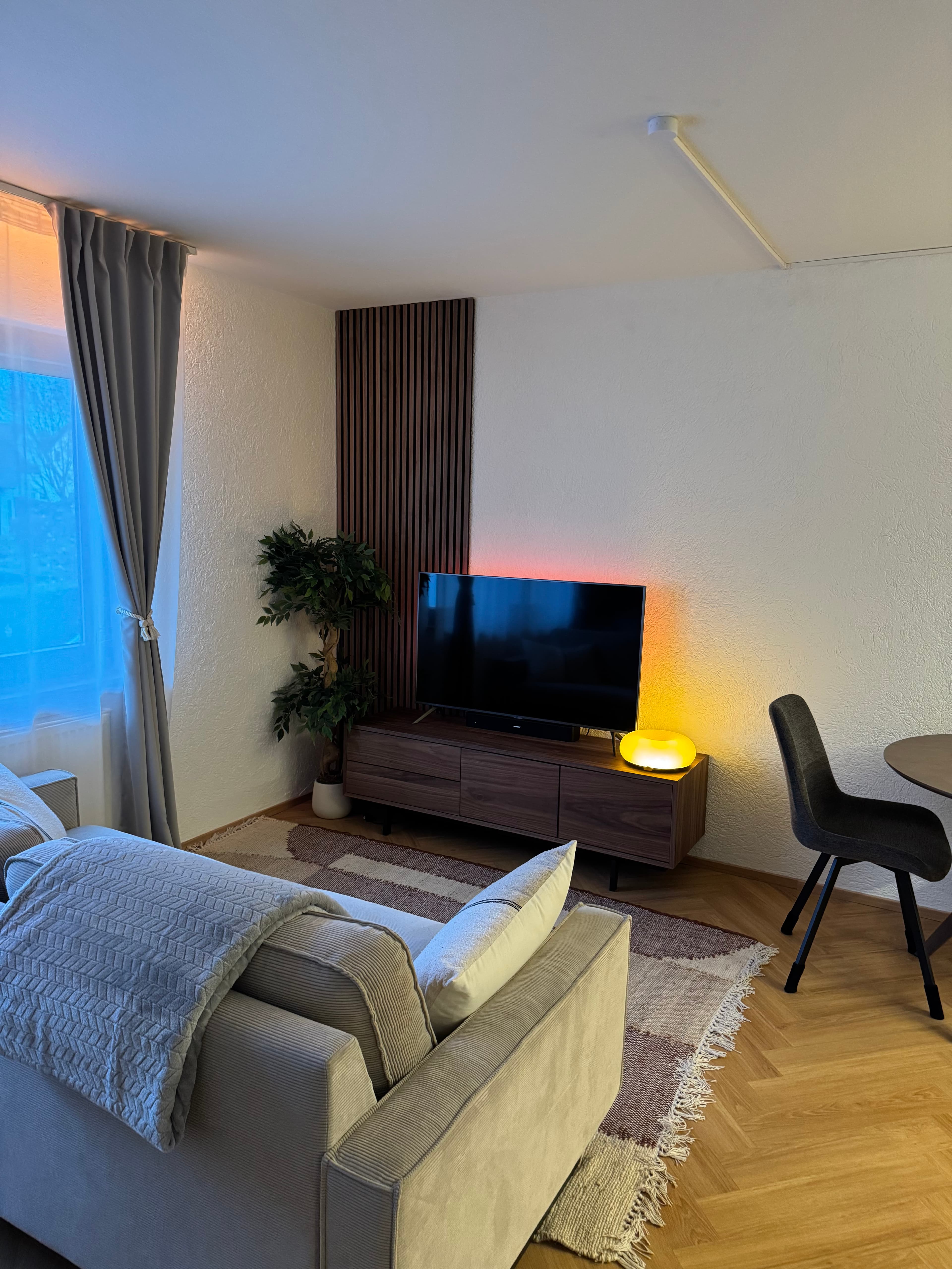 Salon z sofą, komodą z orzecha i ciepłym światłem lampy